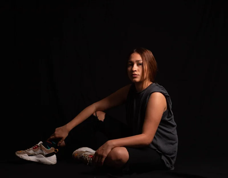 Retrato de estudio de una mujer sentada sobre fondo negro