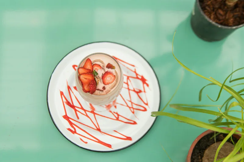 Postre con fresas fotografiado sobre una mesa turquesa