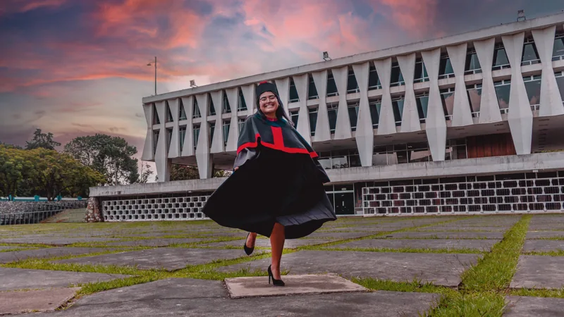 Retrato de una mujer con vestido negro y rojo frente a un edificio